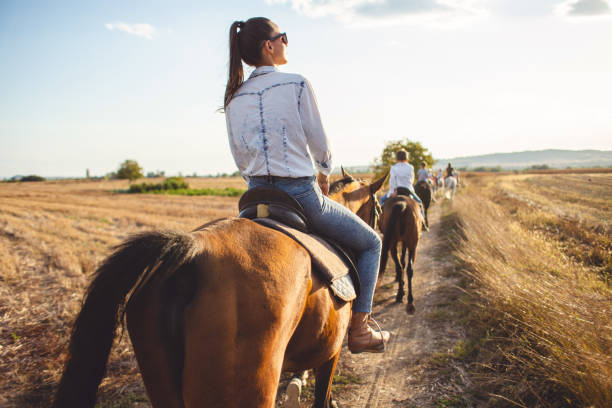 Beautiful woman enjoying horseback riding in nature with friends.